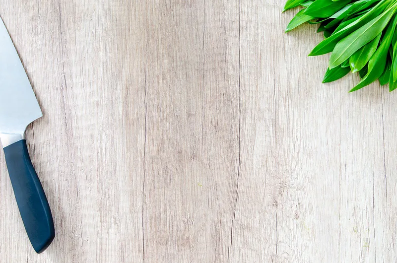 Wooden board with herbs and chef knife