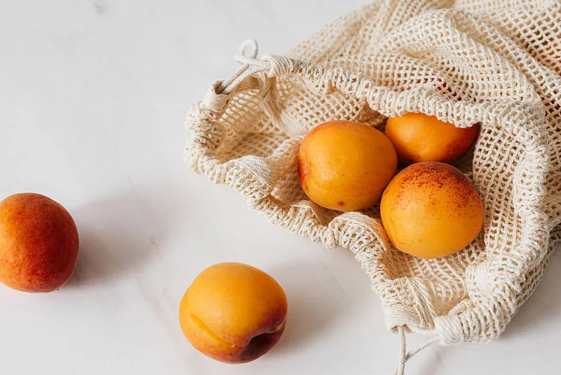 Fresh peaches spilling from a mesh bag